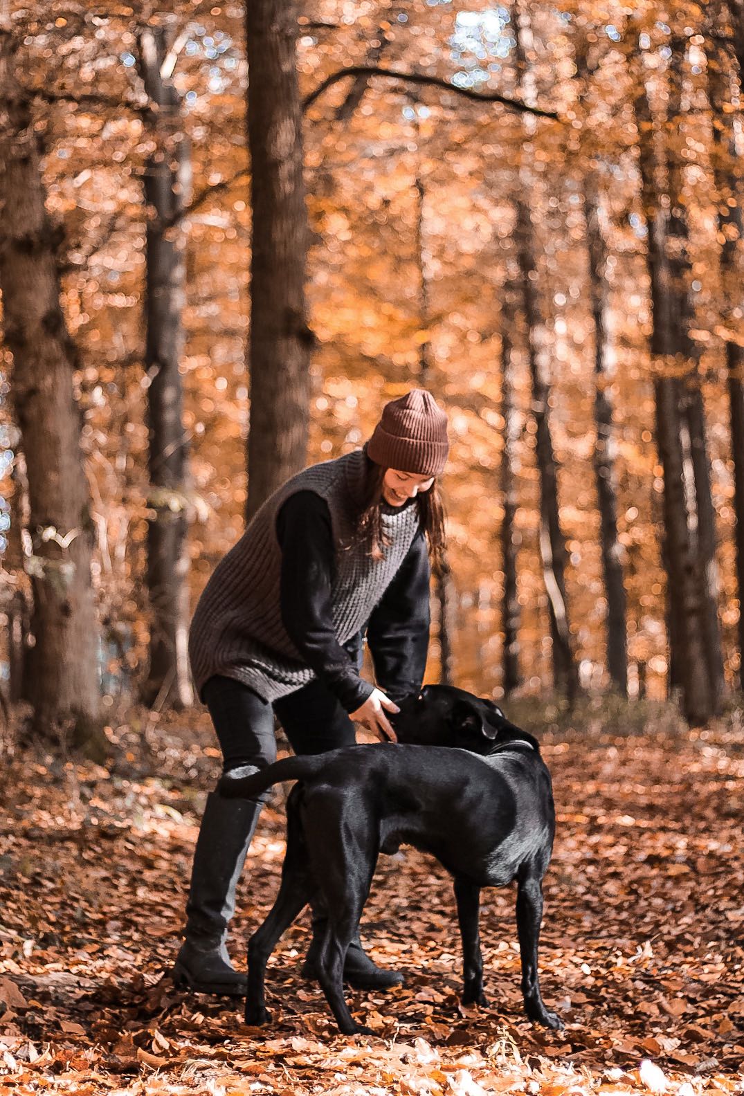 Frau mit schwarzem Hund im herbstlichen Wald
